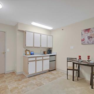 A compact kitchen and dining area featuring white cabinets and a small table set in a minimalist design.