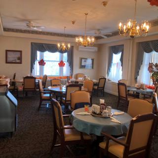 A cozy dining area with elegant chandeliers and neatly arranged tables.