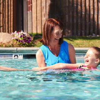 A joyful moment at the pool as a mother helps her child enjoy swimming on a sunny day.