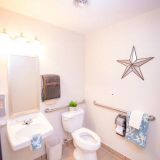 A clean and modern bathroom featuring a toilet, sink, and decorative elements.