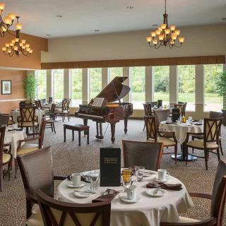 Elegant dining room with a grand piano and large windows.