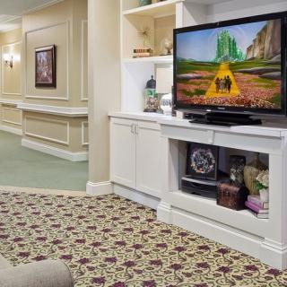 A cozy living room with a television and patterned carpet.