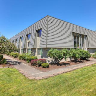 A modern commercial building with well-maintained landscaping and a clear blue sky.
