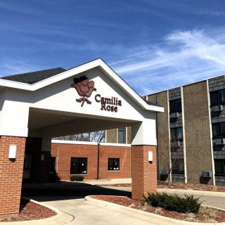 The entrance of a hotel with a visible sign and parking area.