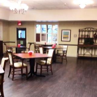 Spacious dining area with tables and chairs on a wooden floor, well-lit with interior decor.