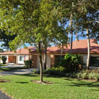A suburban house with a manicured lawn and mature trees.