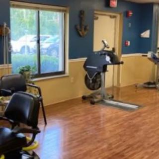 A small fitness room with exercise equipment and chairs.