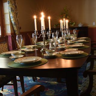 A beautifully set dining table with lit candles and elegant place settings, ready for a formal dinner.