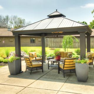 A cozy outdoor gazebo with comfortable seating and lush greenery.