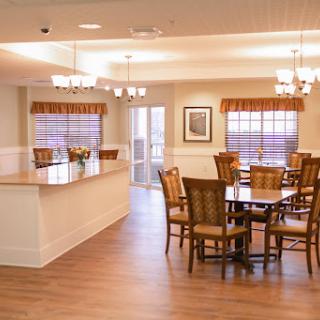A bright and welcoming dining area featuring wooden furniture and large windows.