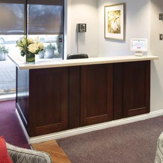 A cozy reception area with a wooden desk and floral arrangement.