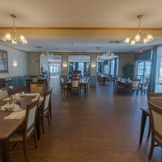 An elegant dining area featuring neatly arranged tables and chairs with ambient lighting.