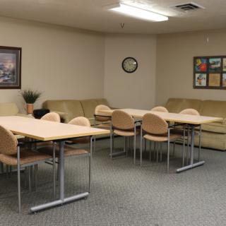 A community meeting room with tables, chairs, and sofas.