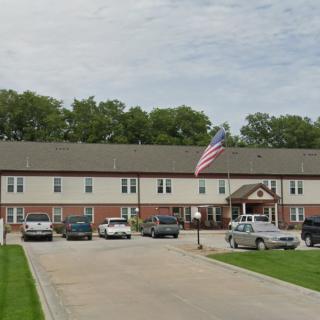 A residential building with a parking lot, several cars, and an American flag.