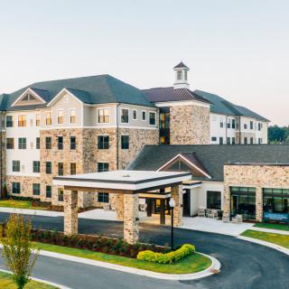 Modern hotel building with a stone facade and landscaped entrance.