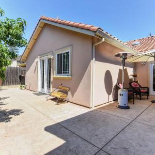 A sunny backyard patio area with garden furniture and a sunshade.