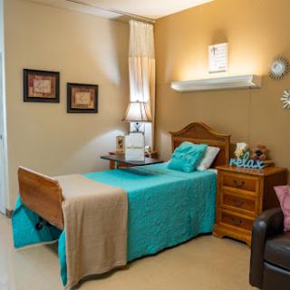 A cozy and well-decorated bedroom featuring a comfortable bed with colorful bedding, complemented by tasteful wall art and furniture.