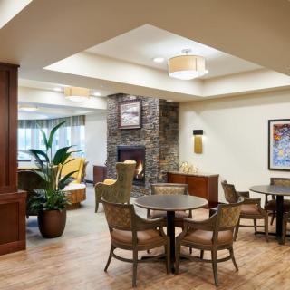 A cozy lounge area featuring a fireplace, comfortable seating, and decorative plants.