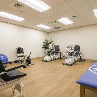 A clean and organized physical therapy room equipped with exercise machines and chairs.