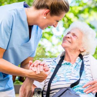 A caregiver connects warmly with an elderly woman, showcasing compassion and support in a serene outdoor setting.
