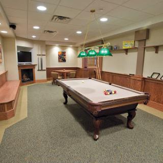 A spacious and inviting game room featuring a classic pool table and comfortable seating.