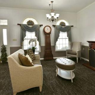A classic and elegant living room with a grandfather clock, plush seating, and tasteful decor.