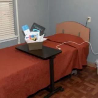 A hospital room with a single bed and medical equipment on a tray table.