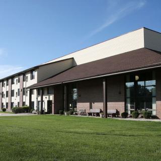 Exterior view of a hotel with a neatly maintained lawn and clear blue sky.