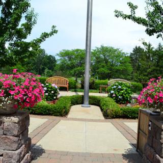 A serene park entrance adorned with vibrant flowers and inviting benches.