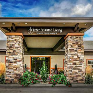 Front entrance of a modern assisted living facility with stone pillars and landscaping.