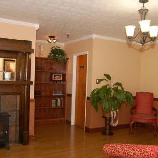 A cozy living room with a fireplace, chandelier, and wooden flooring.