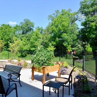 A sunny patio with seating and a view of a lush garden.
