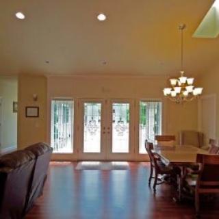 A spacious living and dining area with hardwood floors, a chandelier, and ample natural light coming through the glass doors.
