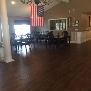 A spacious dining area with an American flag hanging from the ceiling, featuring multiple tables and chairs on a wooden floor.