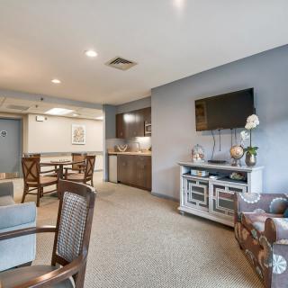 A modern open-concept living and kitchen area featuring stylish furniture and a mounted television.
