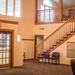 A cozy lobby interior with a staircase and a waiting area with chairs.