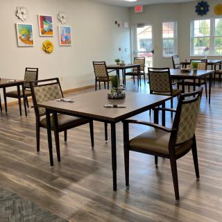 A neatly arranged dining area with several tables and chairs, featuring wooden flooring and wall decorations.
