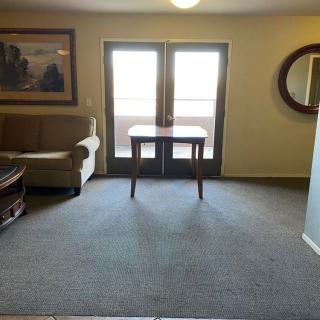 A cozy living room with a sofa, small table, and carpet, featuring a painting and mirror on the walls.