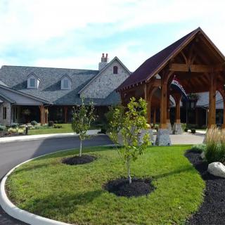 A picturesque building entrance with neatly landscaped greenery and a curved driveway.