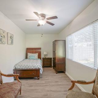 A cozy bedroom with a single bed, wooden furniture, and a ceiling fan.
