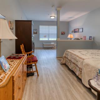 A cozy bedroom with a neatly made bed and classic wooden furniture.