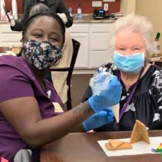 A healthcare worker administering a vaccine to an elderly patient, both wearing masks for safety.