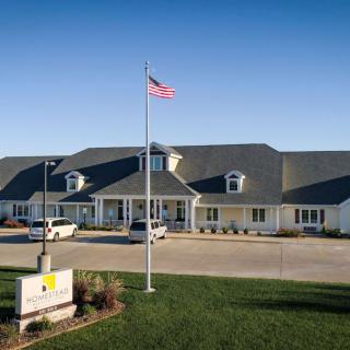 A residential-looking building with an American flag in front and a small parking lot.