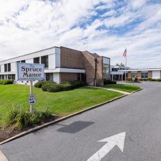 Entrance of a facility with clear signage and landscaping, featuring an American flag.