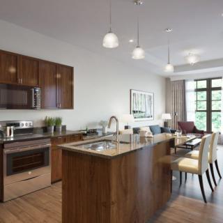 A modern kitchen and dining area featuring wood cabinets and an island with pendant lighting.