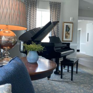A stylish living room featuring a grand piano, modern decor, and elegant furnishings.