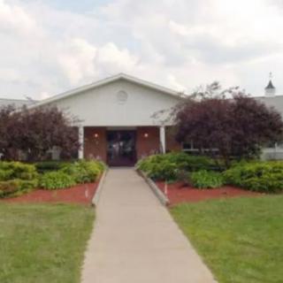 A building with a landscaped pathway leading to its entrance under a cloudy sky.
