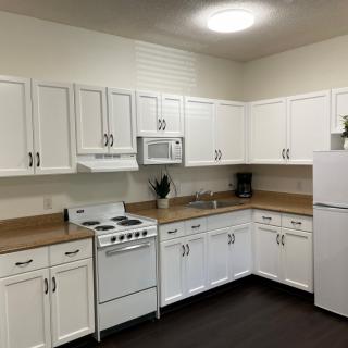 A modern kitchen with white cabinets and appliances including a stove, microwave, and refrigerator.