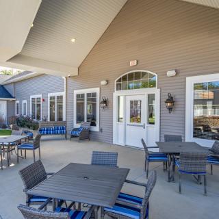 A sunny outdoor patio area with tables and chairs in front of a building.