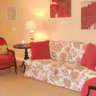 A cozy living room with a floral-patterned sofa, red cushions, and matching decor.